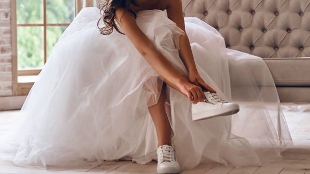a modern bride  wearing a wedding dress puts on sneakers