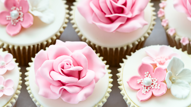 wedding cupcakes with white icing and pink flower decorations on top