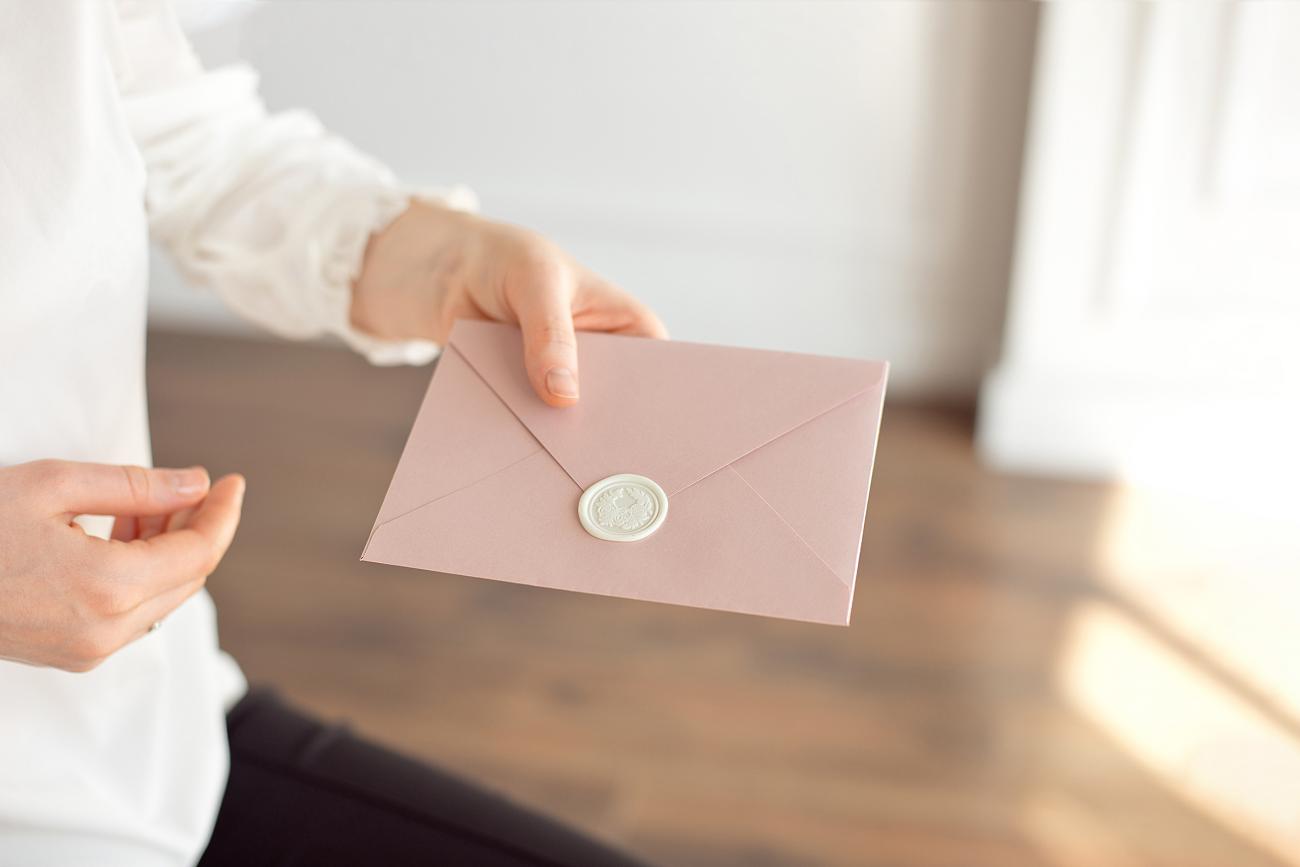 Woman's hands holding a sealed envelope with a wax seal on it
