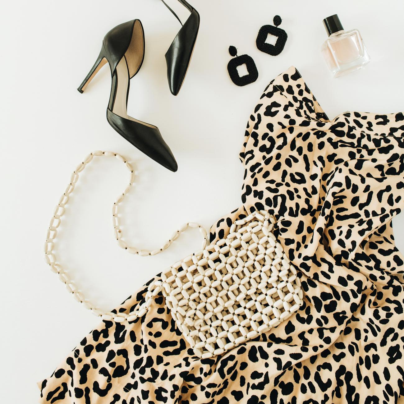 Flatlay with leopard print dress, black shoes, black earrings, and a purse.