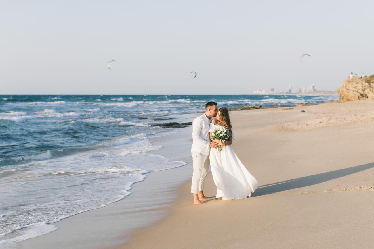 Barefoot bride and groom kissing on the beach