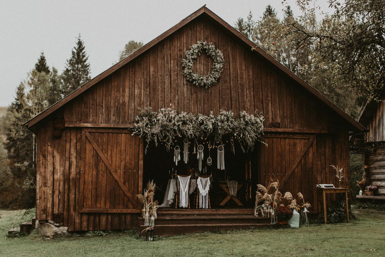 Barn wedding venue decorated with greenery, macramé, and pampas grass