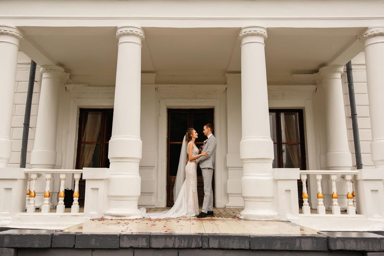 Bride and groom embracing in archway of building with columns