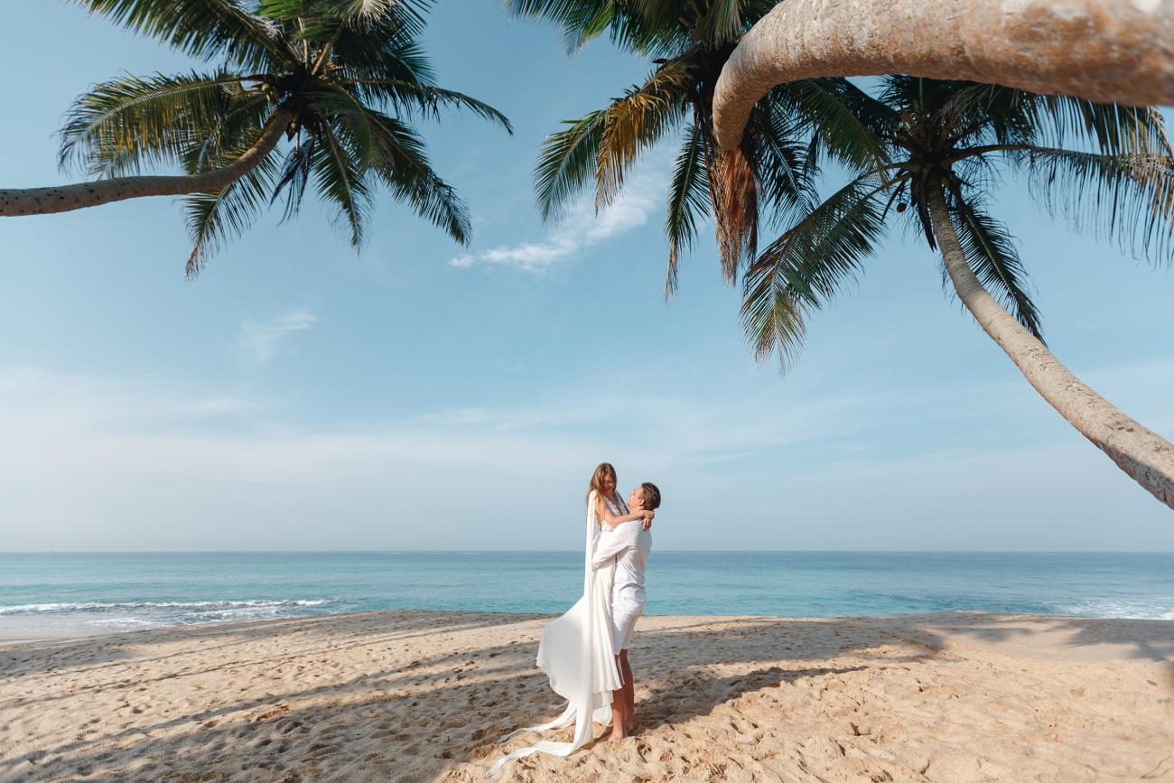 Bride and groom embracing on beach