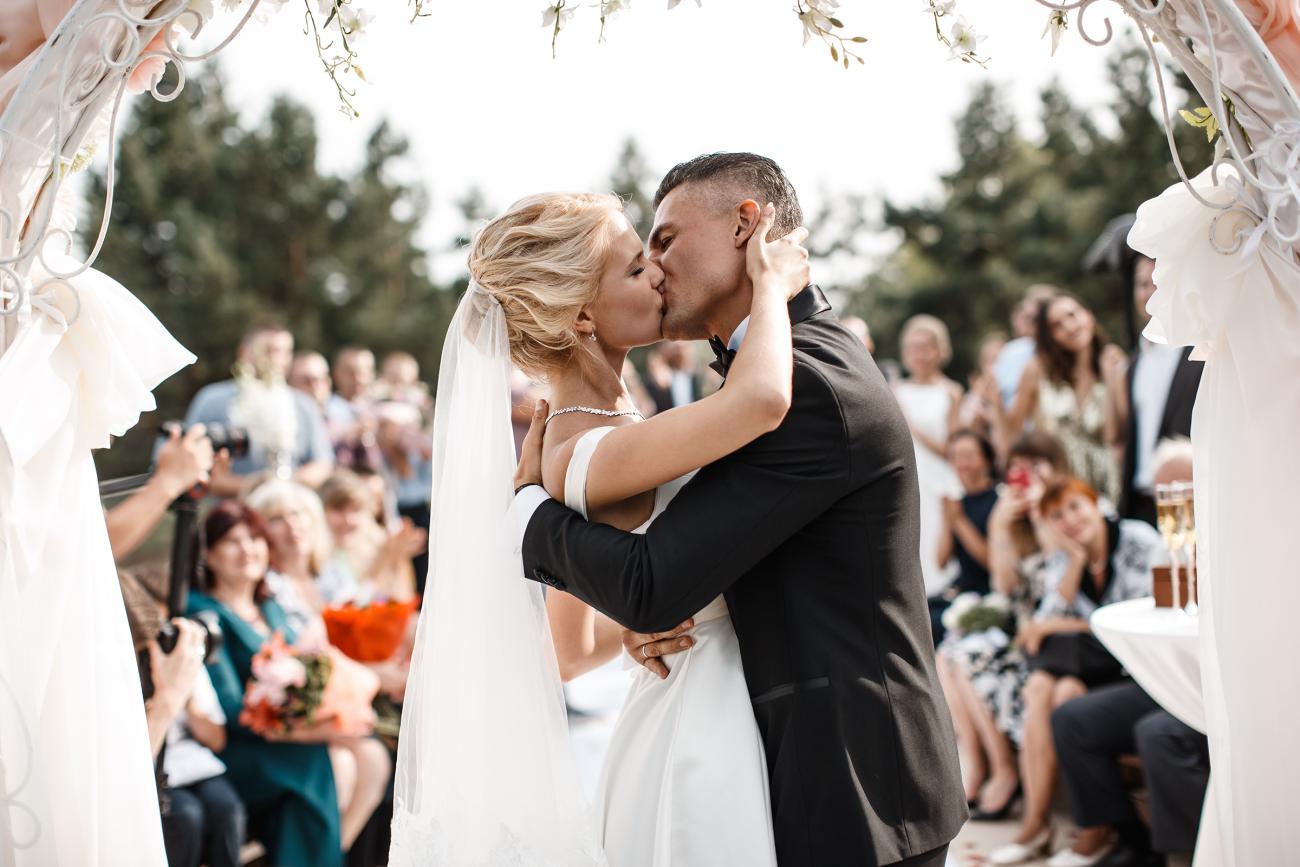 Bride and groom kissing in front of cheering family and friends.