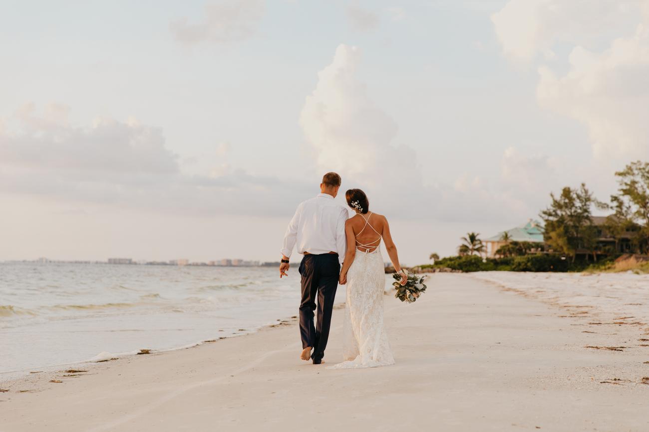 Bride and groom walking hand in hand on the beach