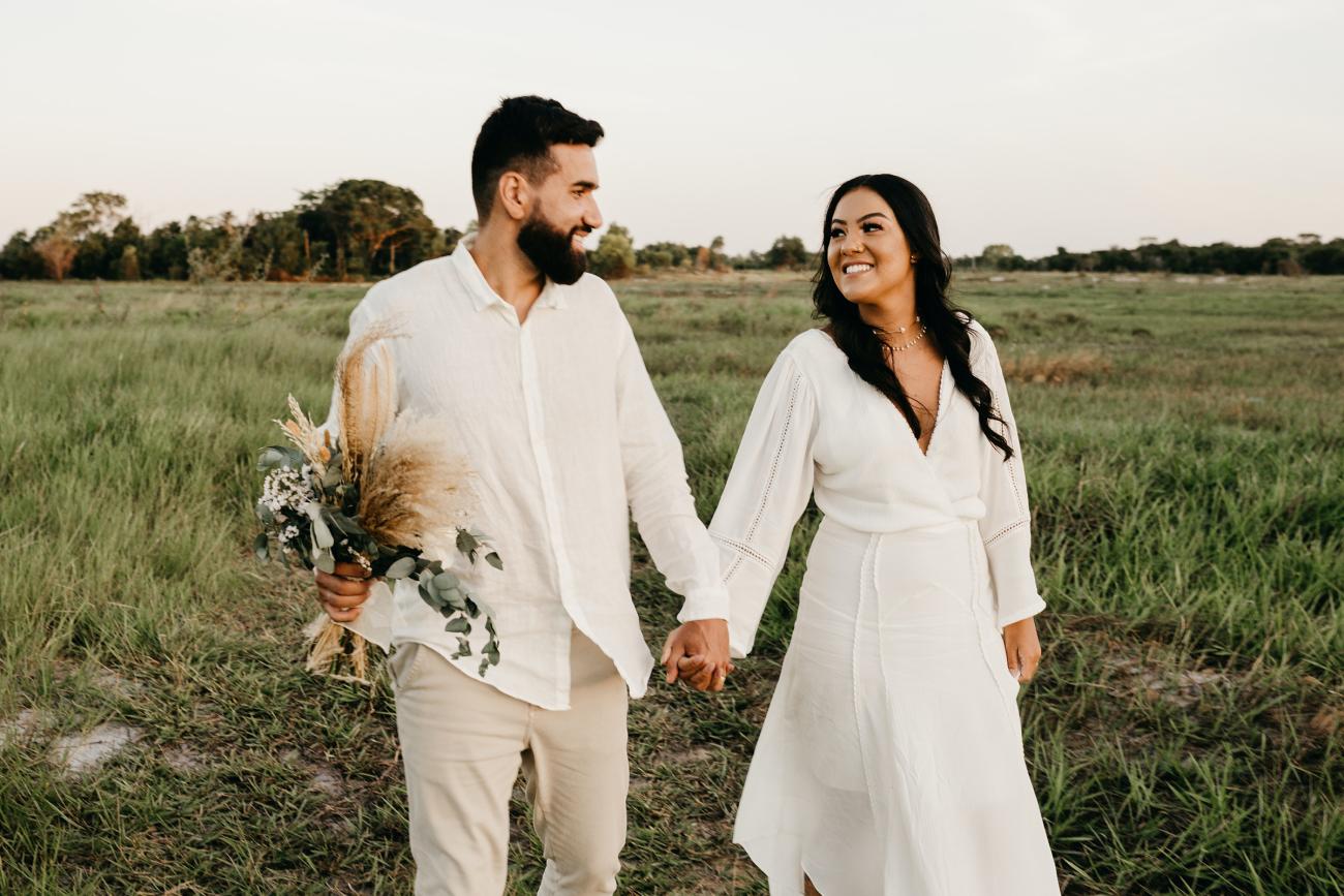 Happy bride and groom holding hands while walking in a field