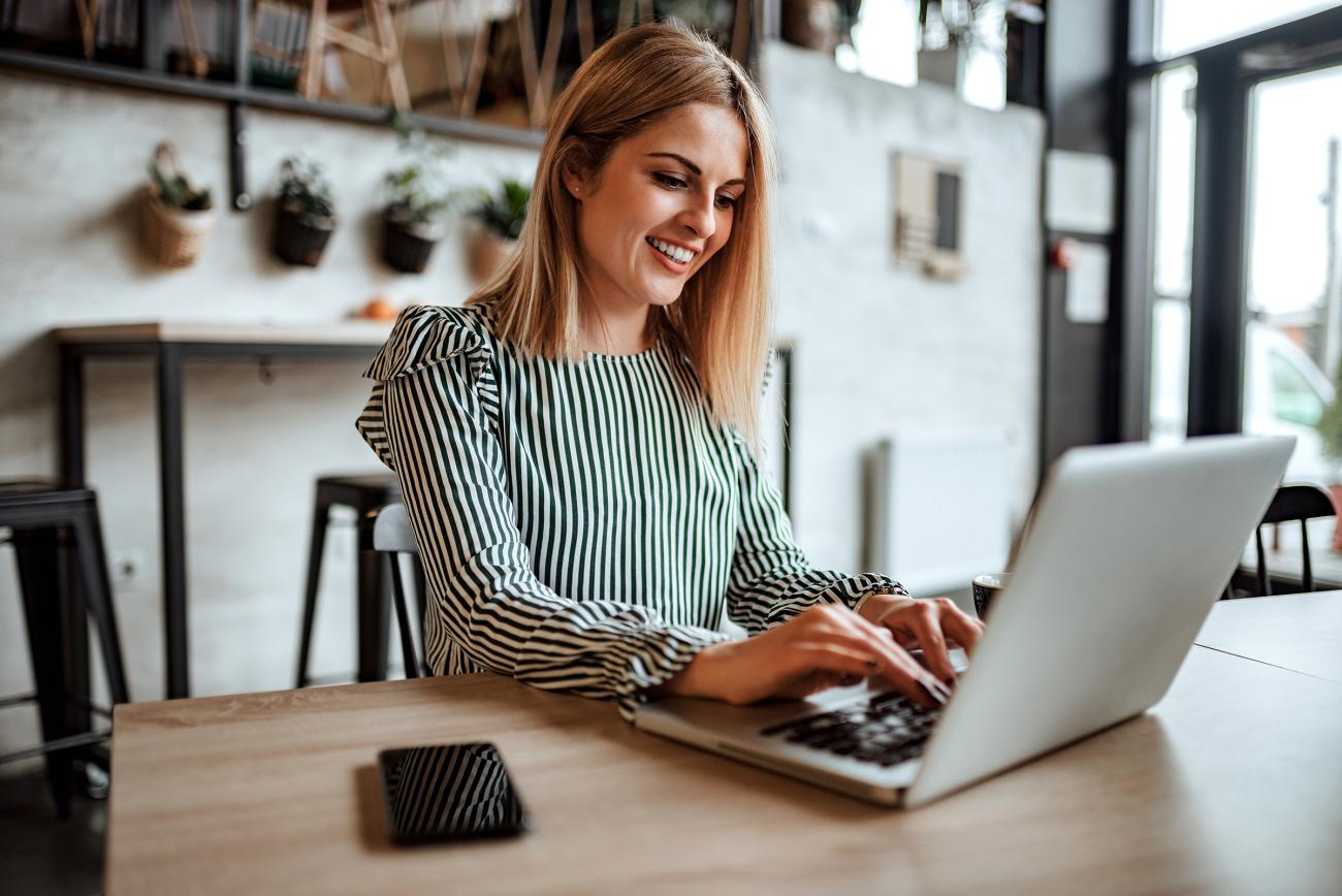 Happy woman working on her laptop in a coffee shop