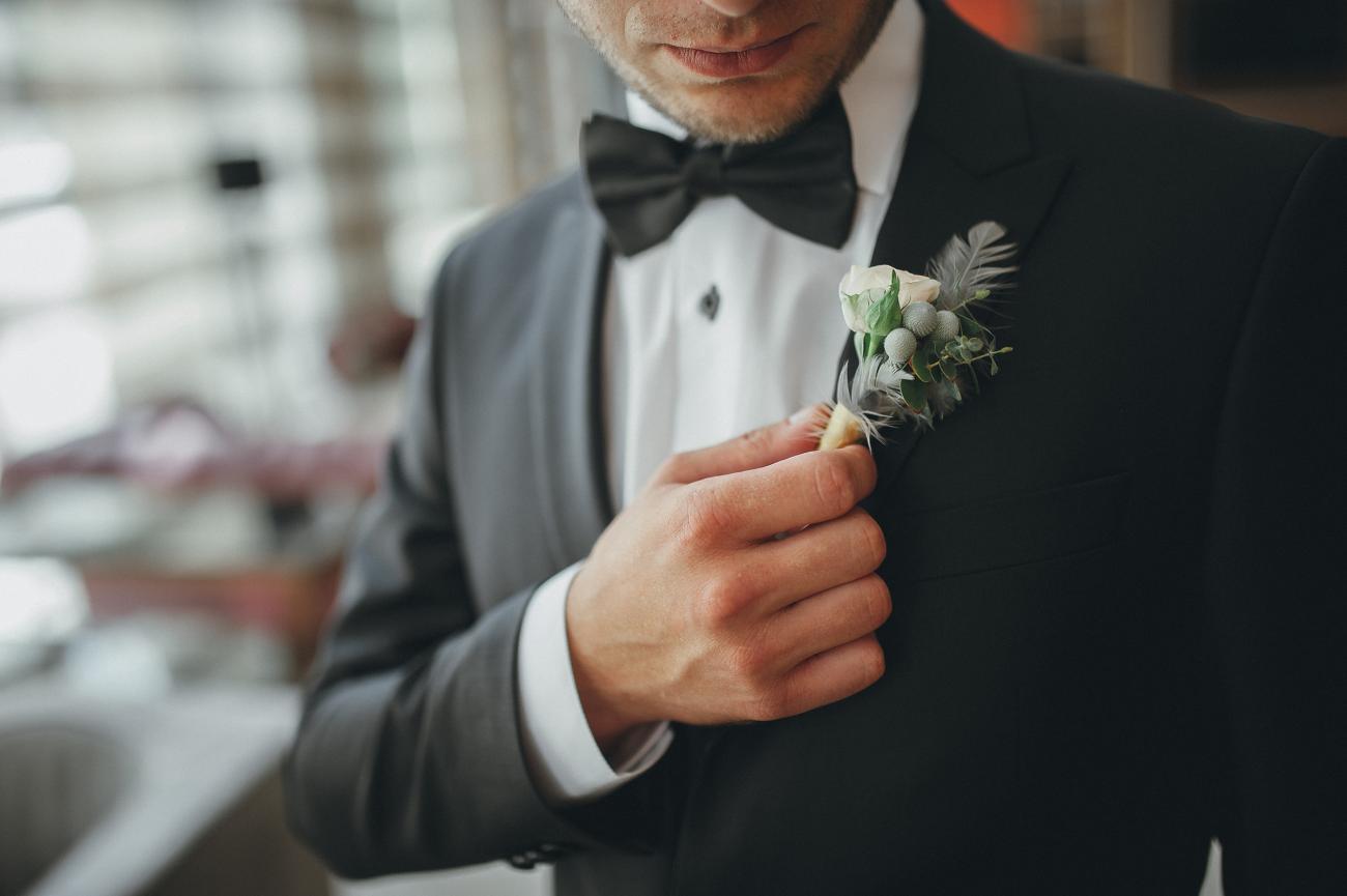 man in tuxedo adjusting his boutonniere