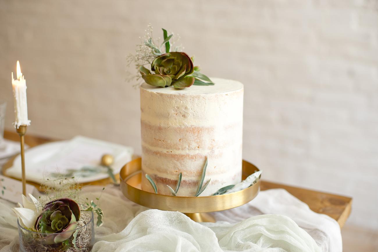Small wedding cake on glad cake stand with decoration around it