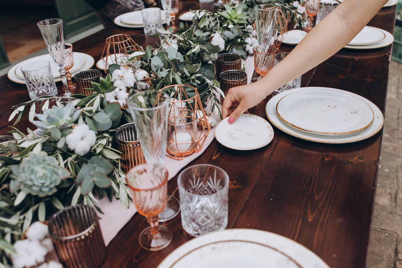 woman setting plates on long table with beautiful florals and decorations
