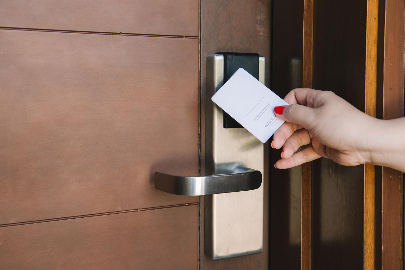 Woman using room key to unlock hotel room door