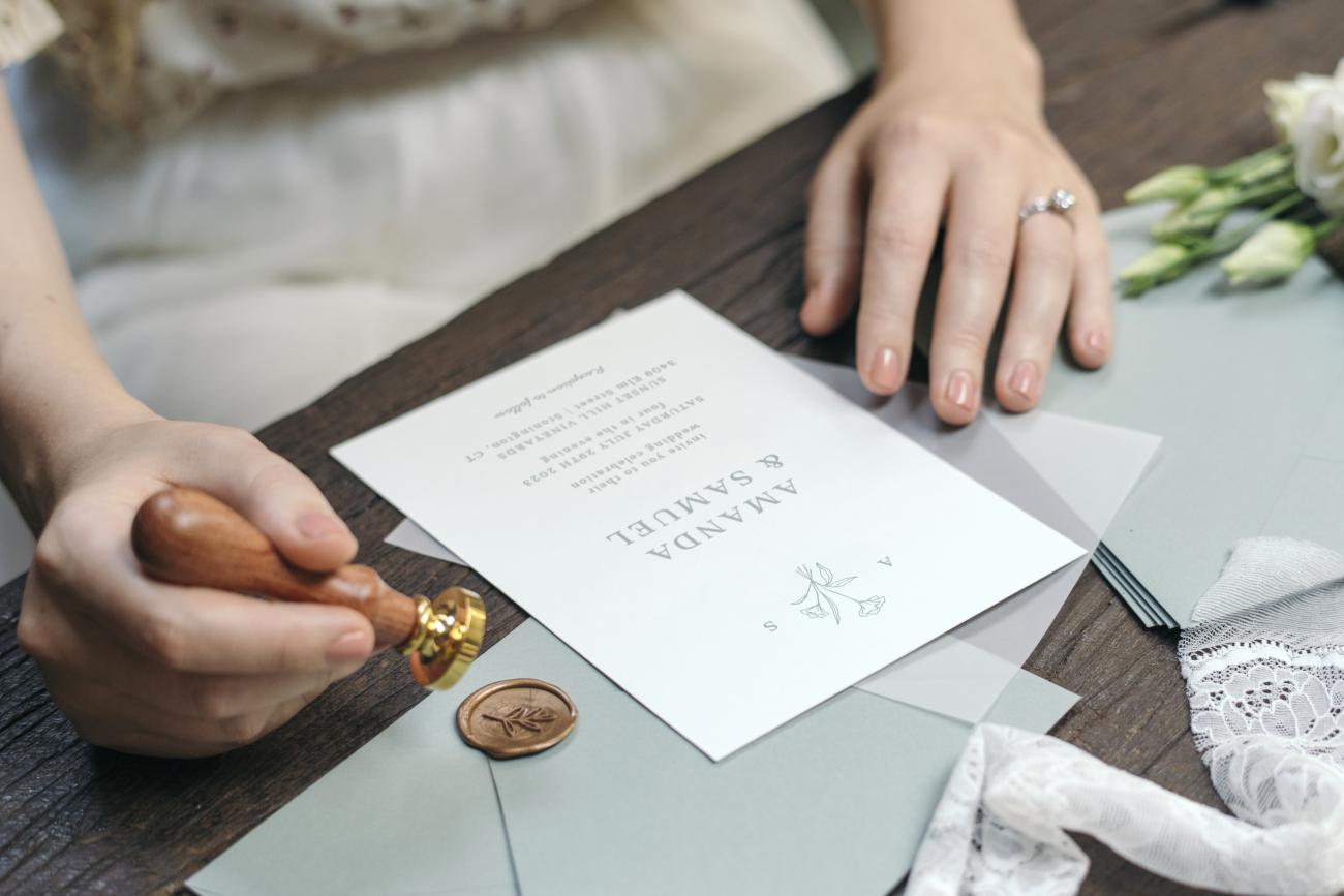 Woman using wax seal to close her wedding invitation envelope