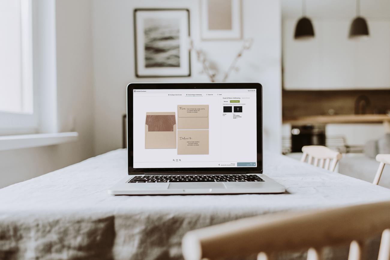Open laptop on table showing envelope and addressing designs
