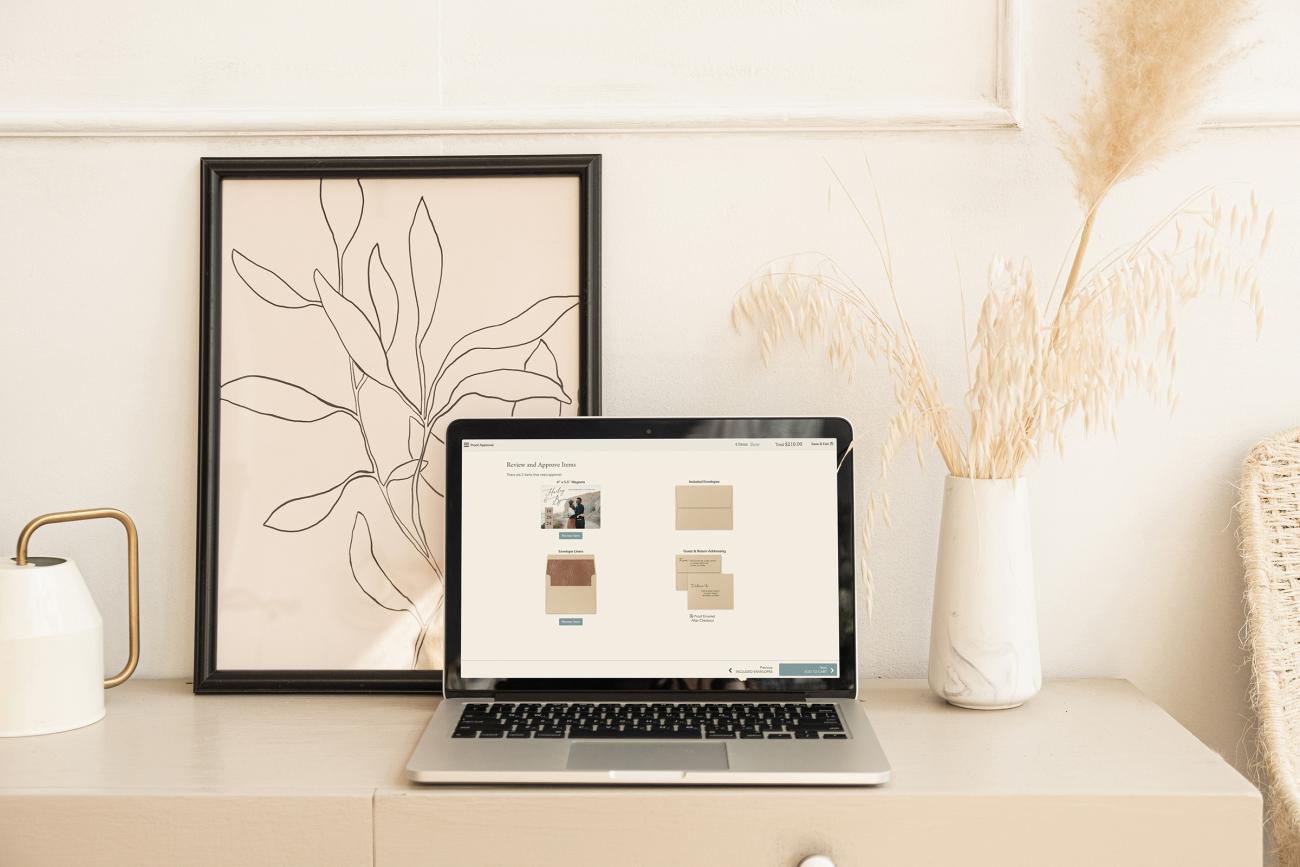 Open laptop showing save the date and envelope design proofs