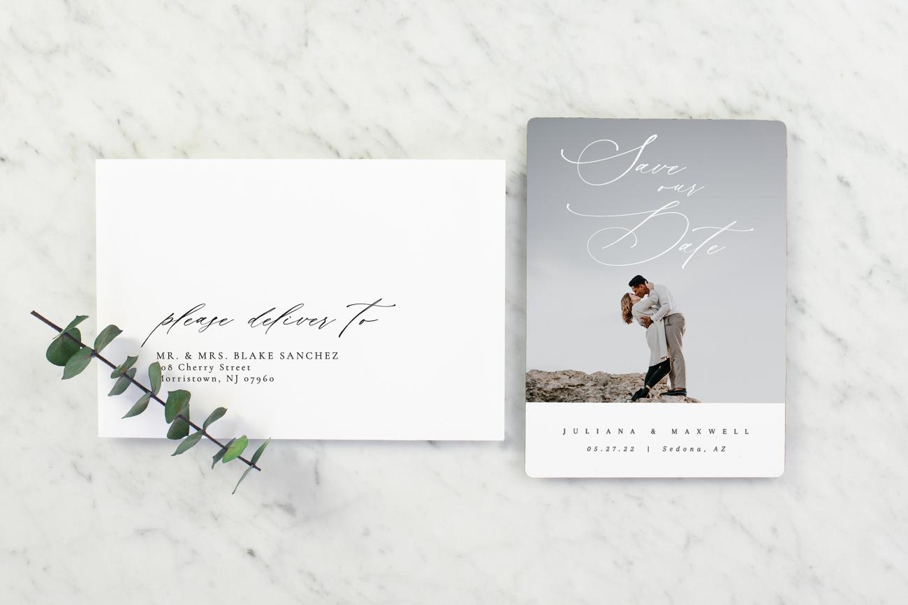 Save the date magnet next to an addressed envelope on marble background