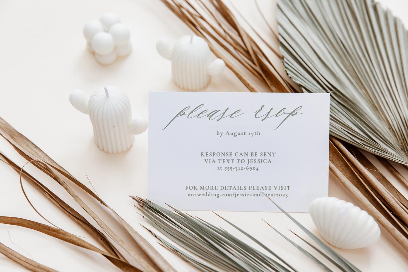 Wedding response card sitting by dried florals and little candles