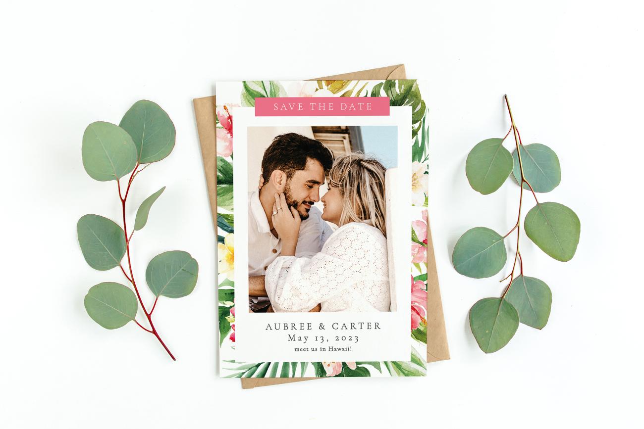 Destination save the date laying on envelope next to eucalyptus. 