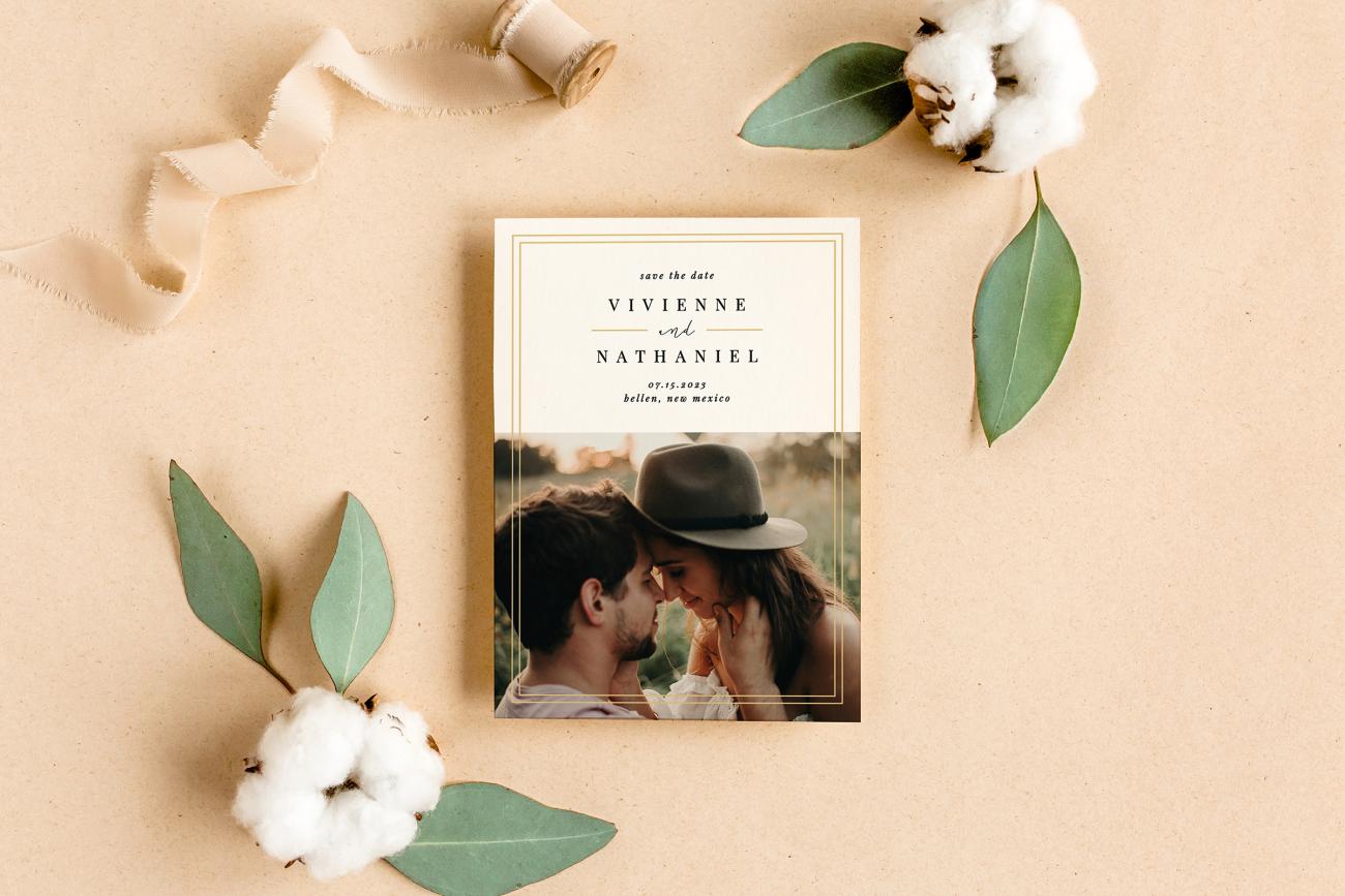 Save the date next to tan ribbon, eucalyptus, and cotton.