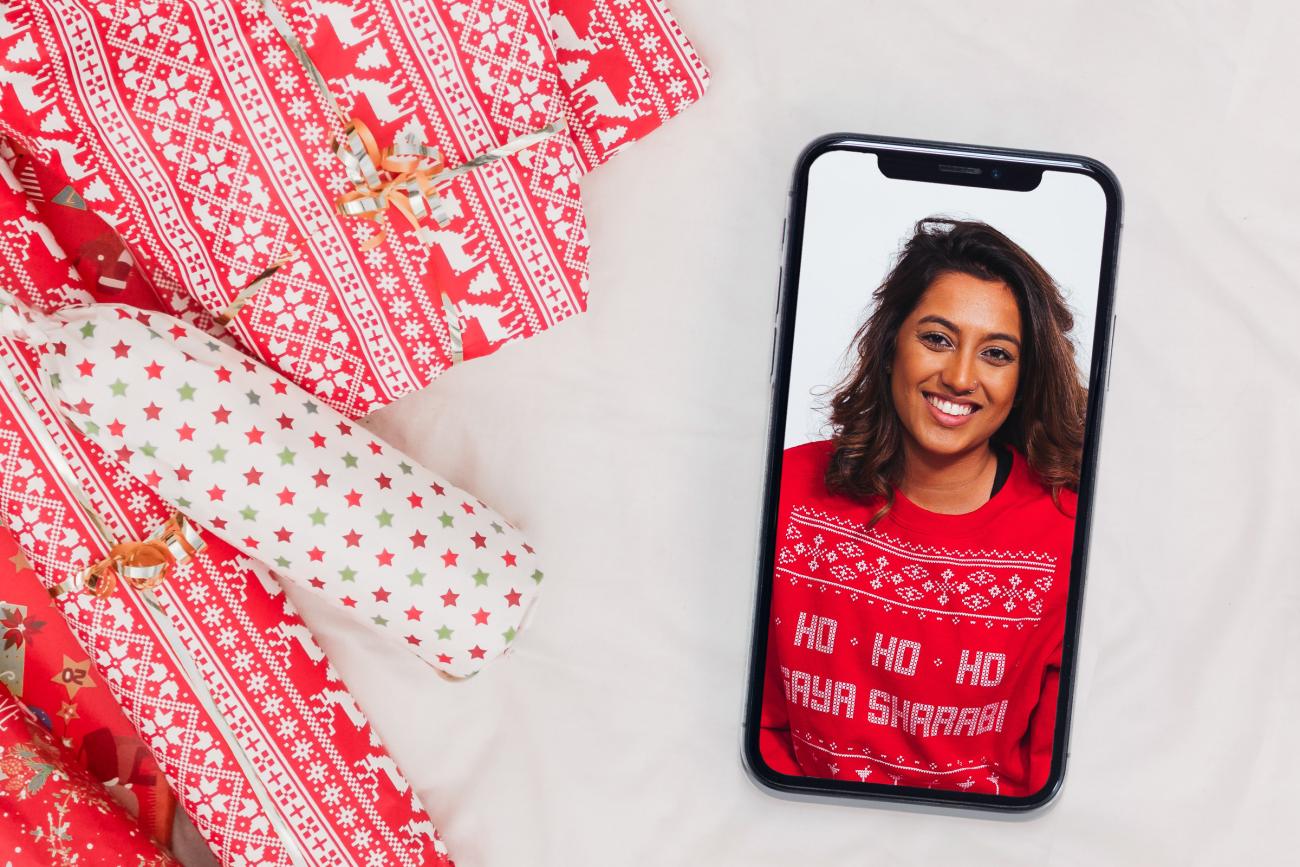 Video greeting on a phone next to Christmas presents