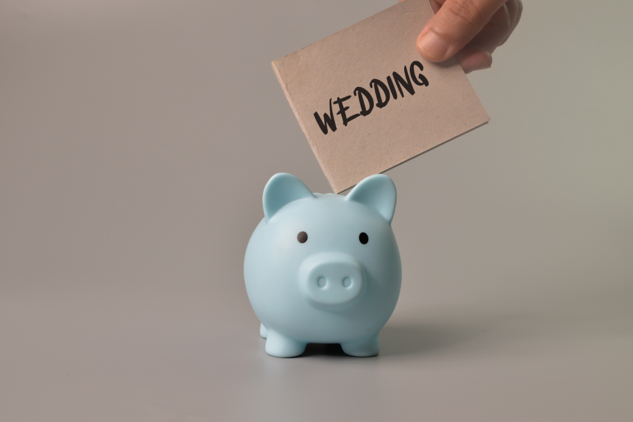 a hand puts a wedding note in a piggy bank
