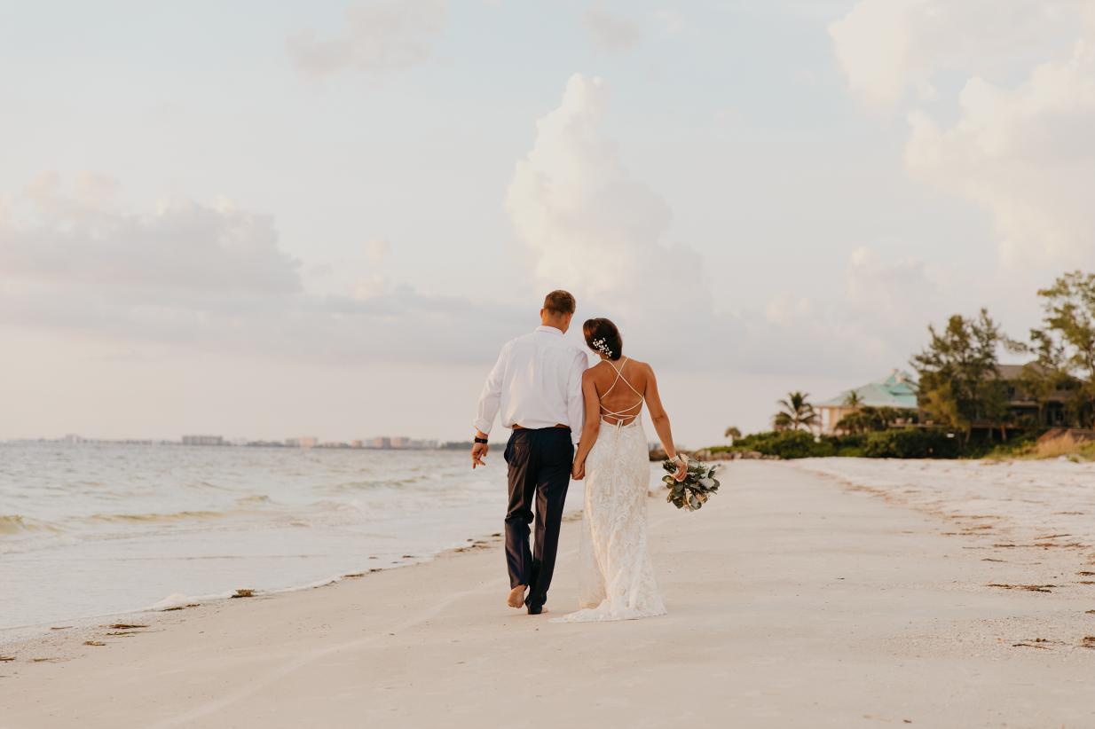 Bride and groom walking hand in hand on the beach