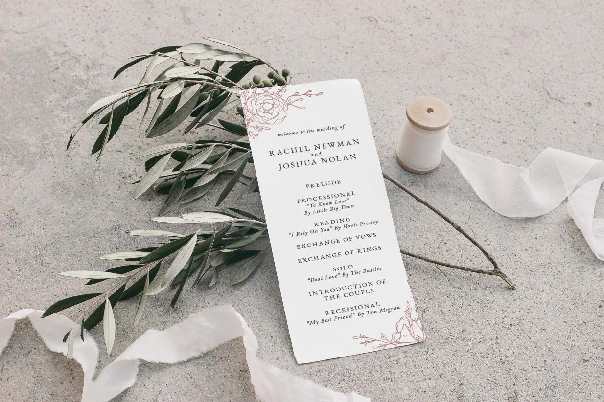 Tea length wedding program leaning against sprig and surrounded by silk ribbon