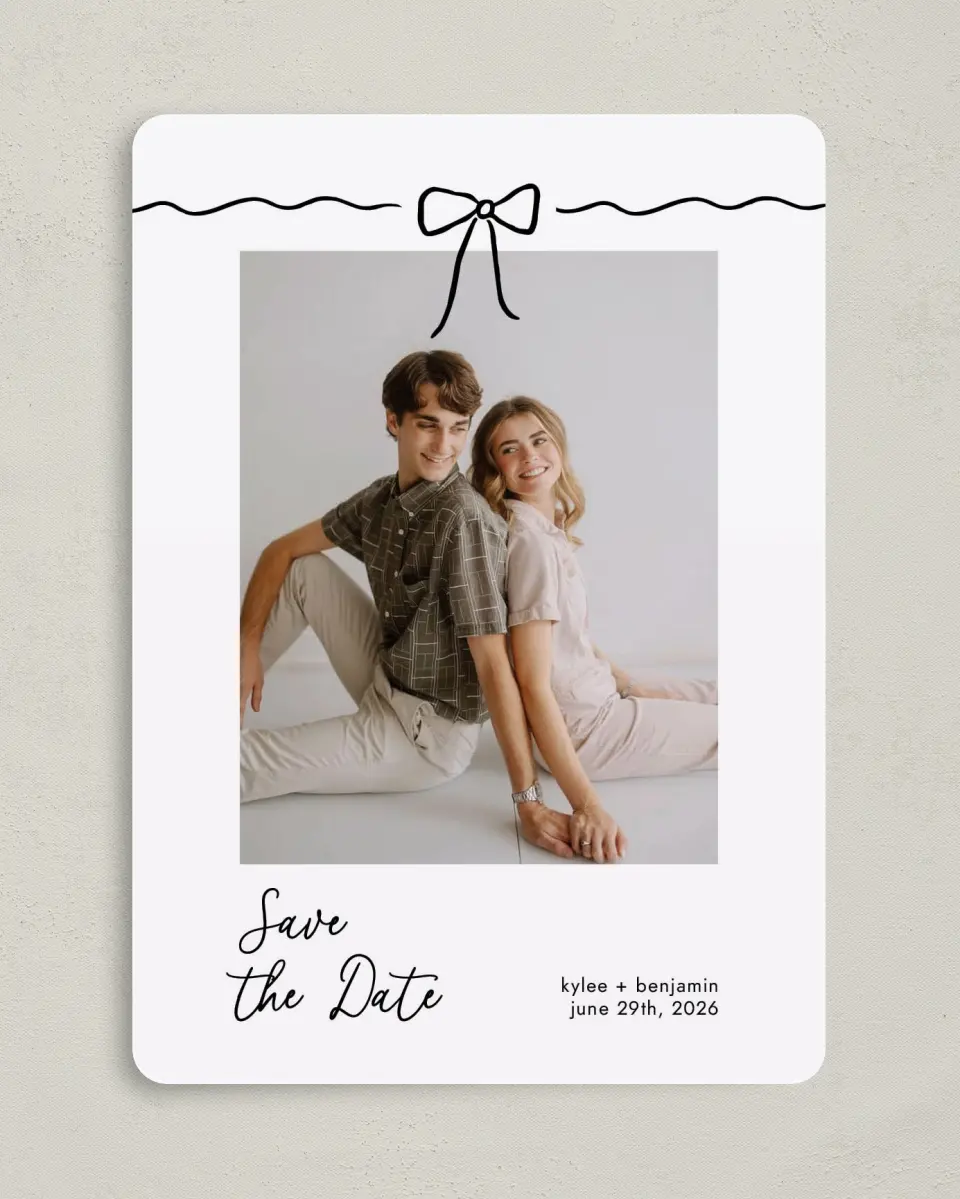 This is a 5" x 7" Save the Date Card called Bows and Bliss printed in full color with Gold foil on Luxe Satin (coated) paper