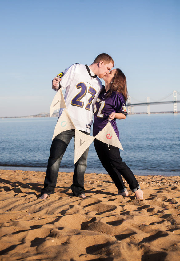 Couple holding a DIY banner sign in their football themed engagement session 