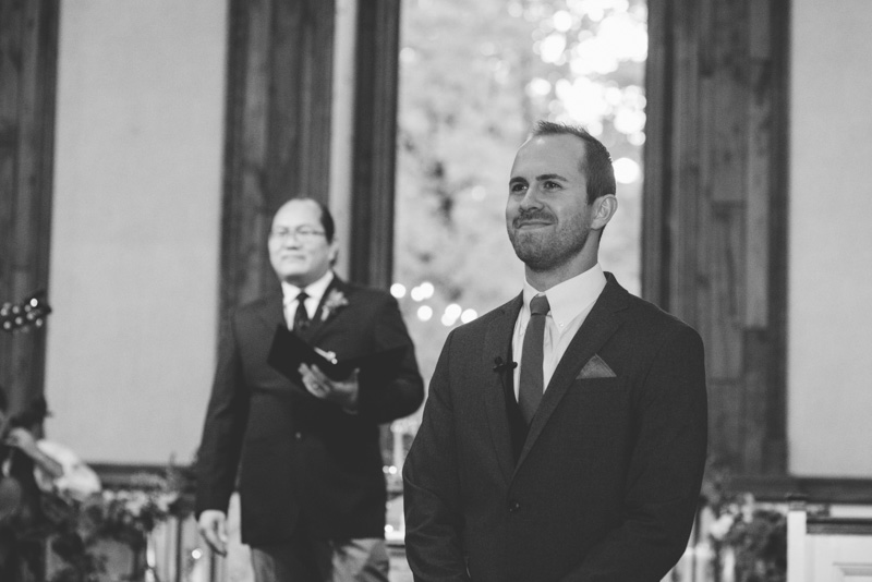 Groom watching bride walk down the aisle