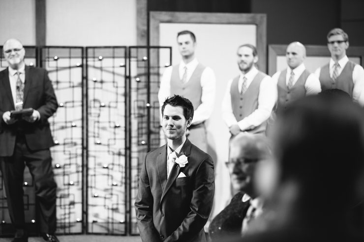 Groom watching bride walk down the aisle